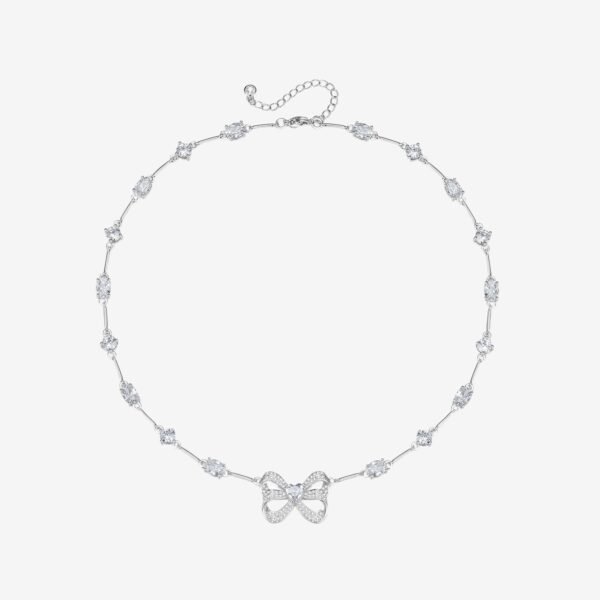A delicate silver necklace features a series of oval gemstones and a central bow-shaped pendant adorned with sparkling stones. The necklace includes an adjustable chain and clasp for fastening.