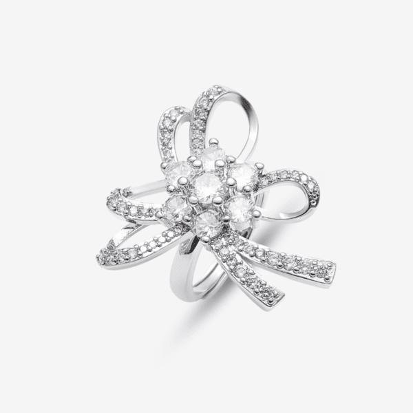 A silver ring with an intricate bow design encrusted with small diamonds and a cluster of larger stones at the center, set against a plain white background.