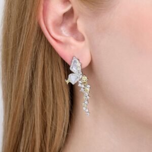 A close-up of a persons ear wearing an intricate earring featuring butterfly designs with a mix of white and yellow stones. The earring drapes elegantly down the earlobe.
