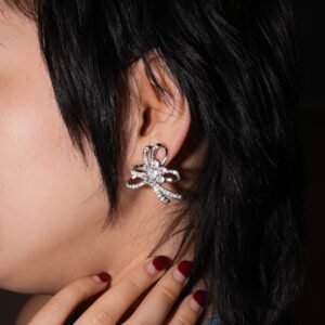 A pair of elegant silver earrings with intricate bow designs and sparkling stones. The earrings feature loops and clusters of gems, creating a luxurious and delicate appearance against a plain white background.